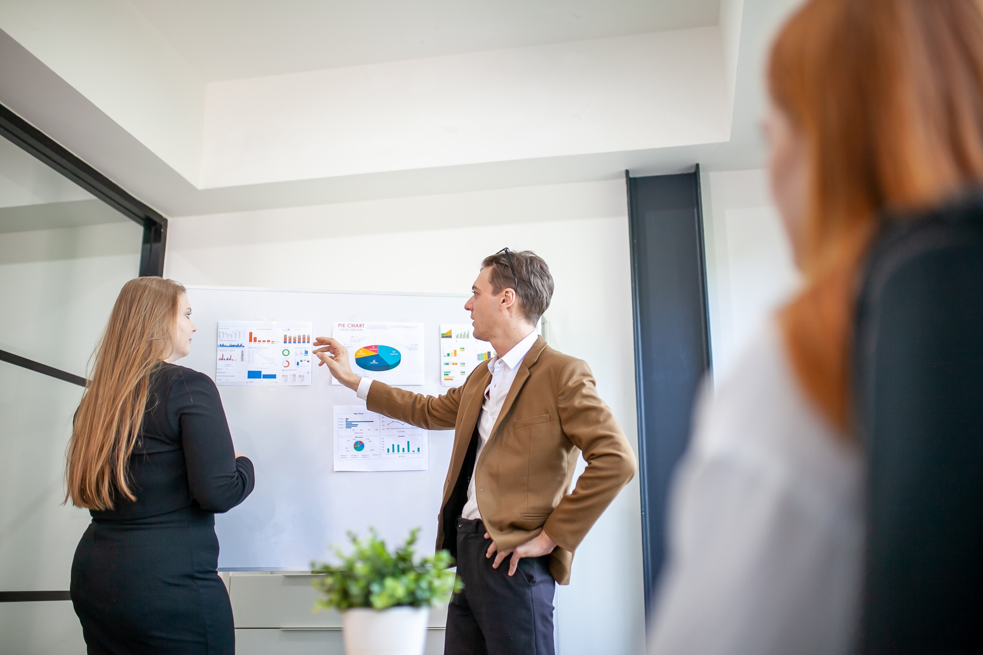 business team male and female colleagues talking at work share ideas with chart on board.