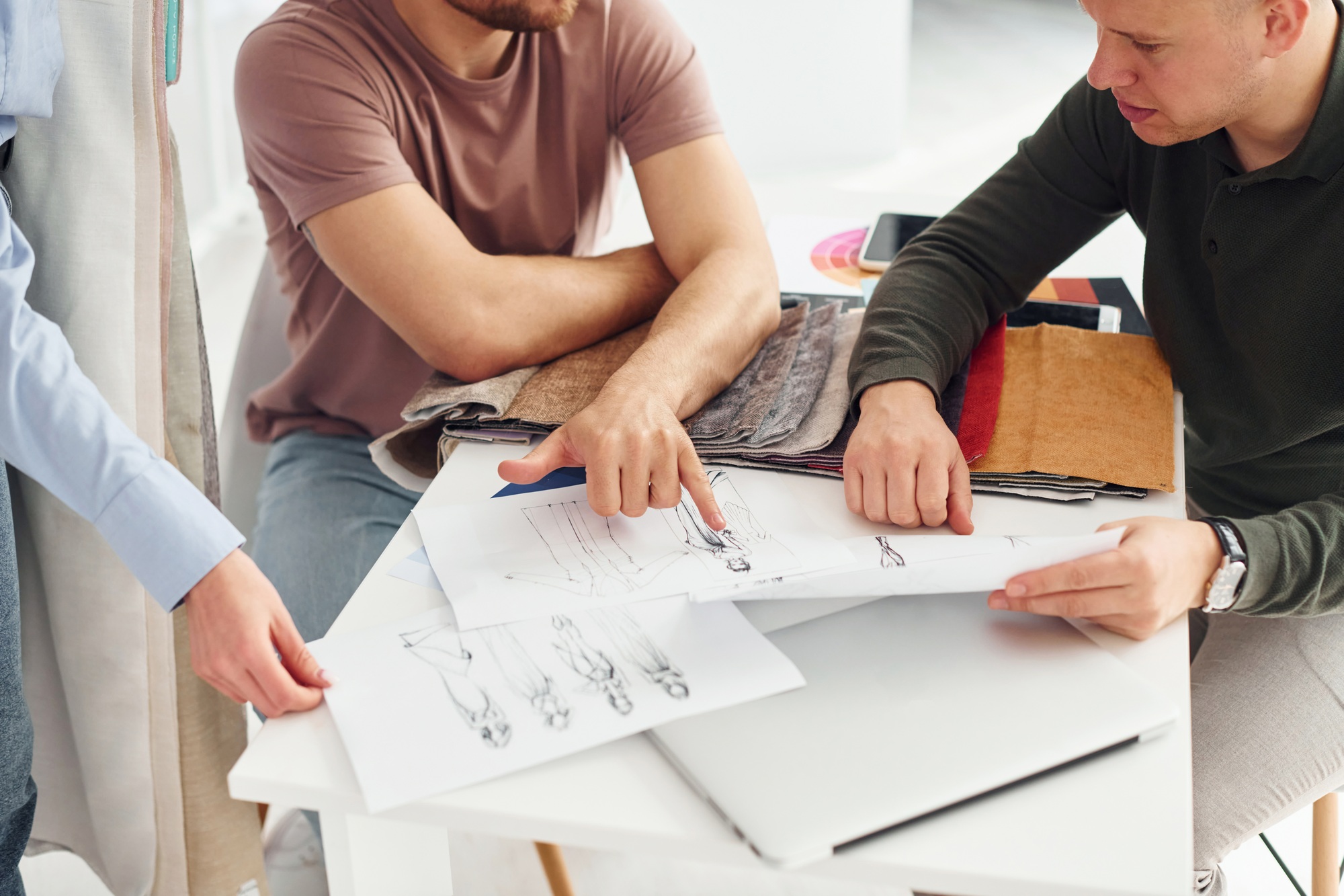 Cloth and fashion business. Three people works in the office by sitting by the table